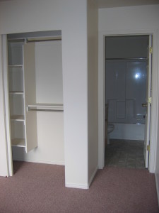 Picture of Master bedroom including closet with built in shelving. You can also see the master bathroom doorway and the tub inside the bathroom. 