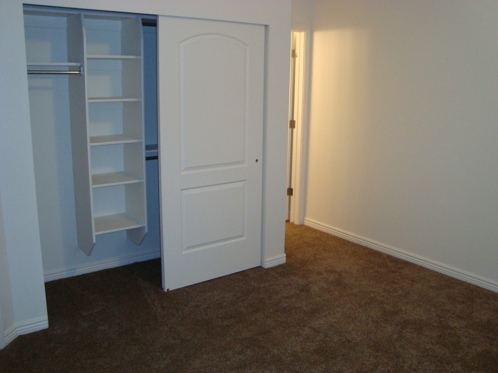 Master bedroom closet with built-in shelves, full length hanging rod and half length hanging rods. 