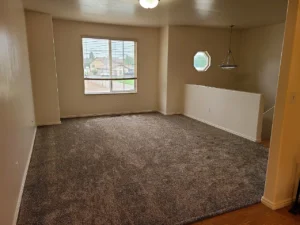 Livingroom showing picture windows and the top of the stairs down to the front door.